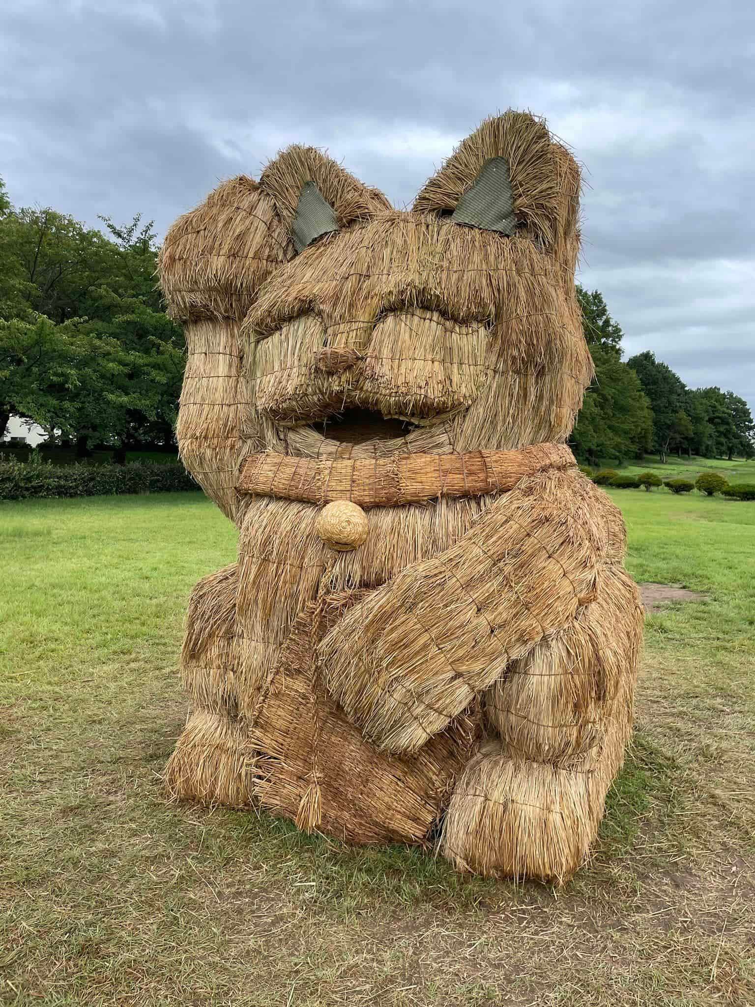 a mammoth beckoning cat sculpture made of straw